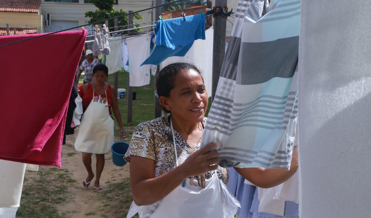 Meirilene colocando uma peça de roupa no varal